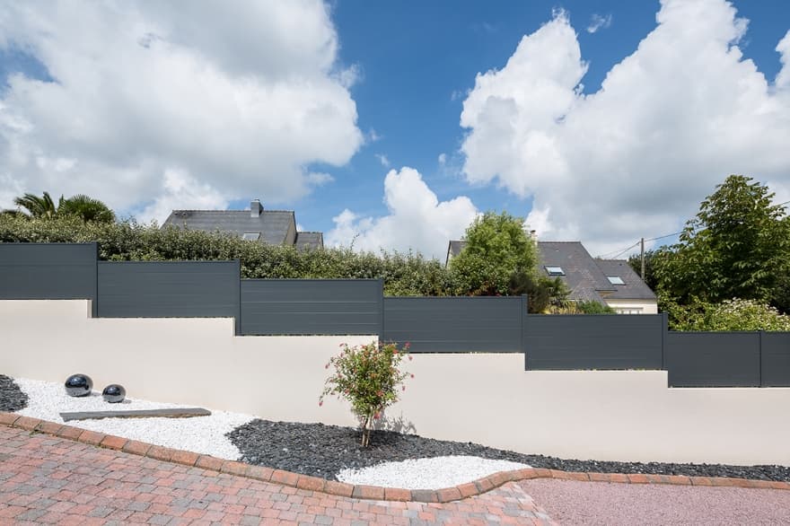 Muret enduit avec clôture en paliers le long d'un jardin